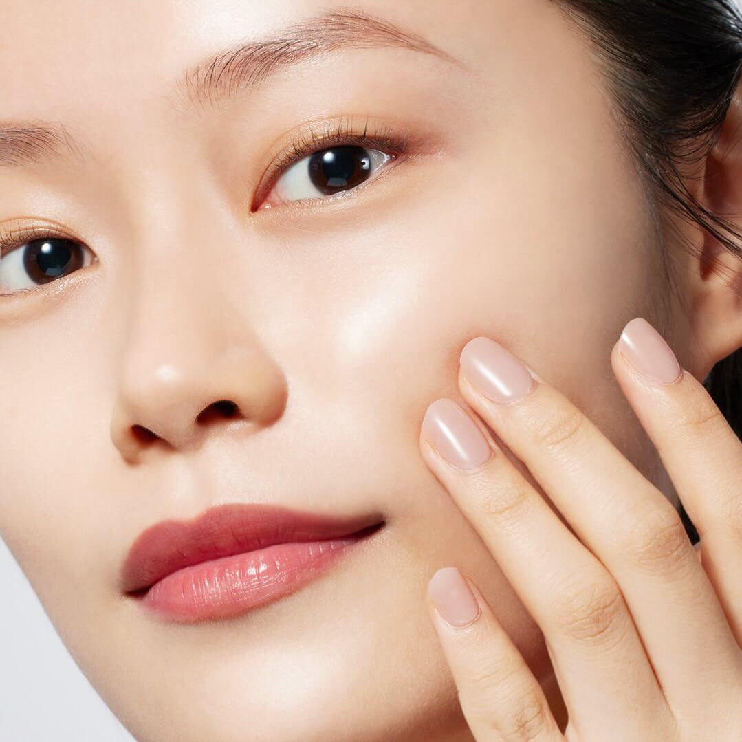 Model applying MOONSHOT Magnetic Black Cleansing Oil on skin for radiant complexion.