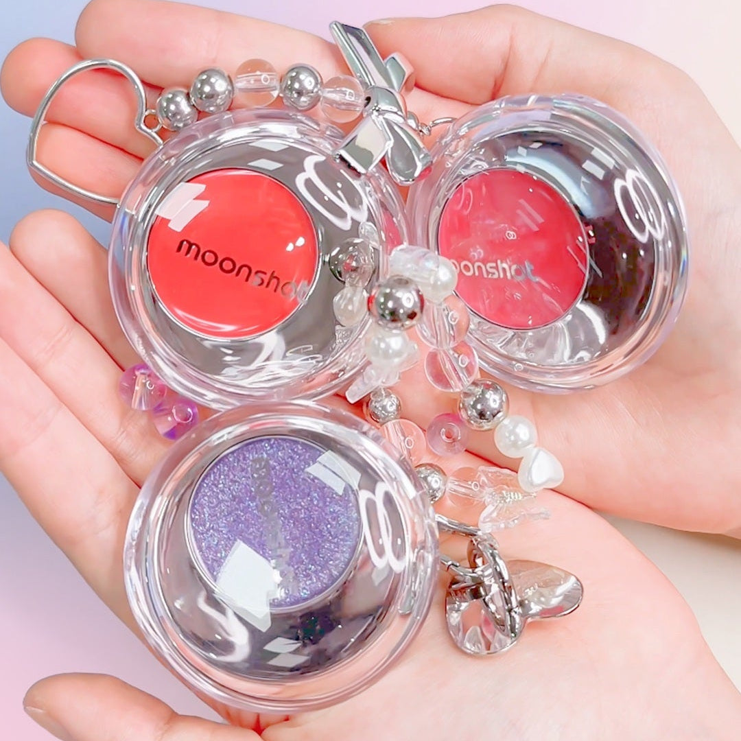 Hand holding colorful MOONSHOT Melting Mood Lip & Cheek products with playful design and vibrant shades for lips and cheeks.