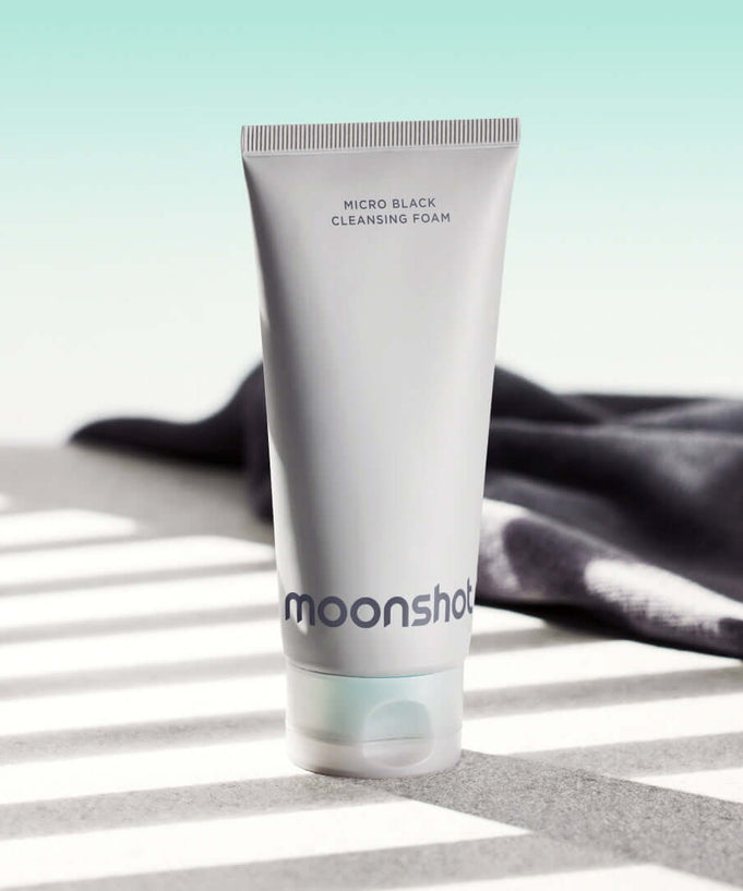 MOONSHOT Micro Black Cleansing Foam tube on a sunny surface with shadows.
