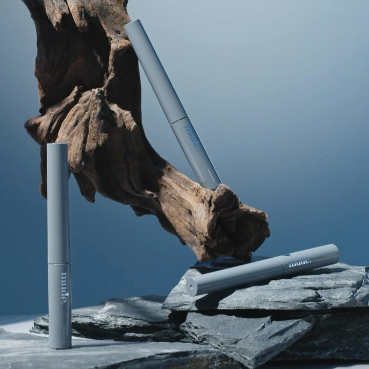 MUDE Eye Eye Ting Ting Serum Shot displayed on stones with artistic wooden backdrop, emphasizing the elegance of skincare packaging.