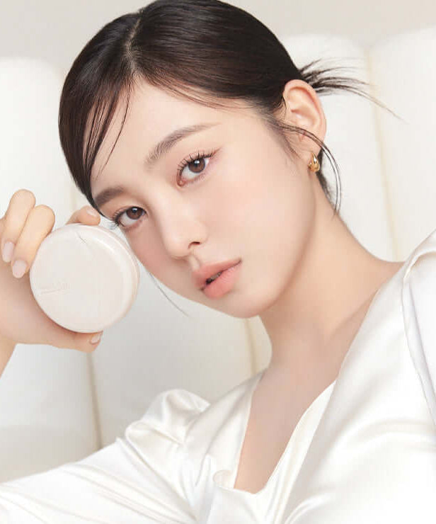 Person holding MUDE Soft Silky Fit Cushion in an elegant setting, showcasing the product's sleek design.