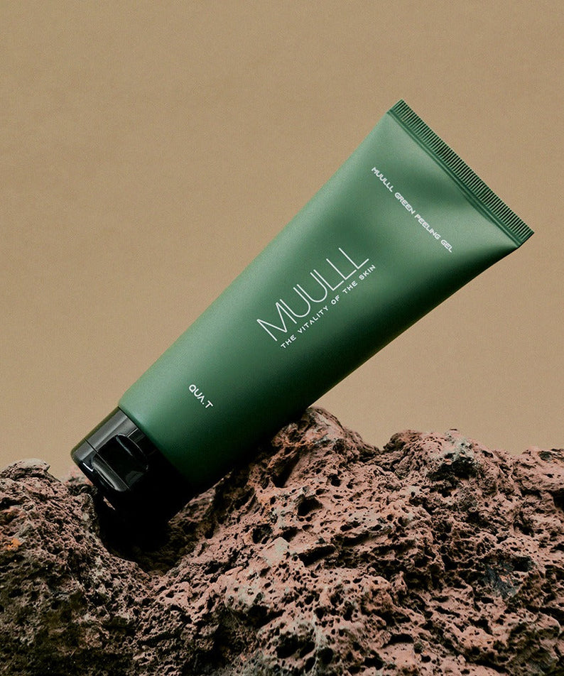 QUA-T Green Peeling Gel 150ml tube on a natural rock surface, highlighting skincare packaging.