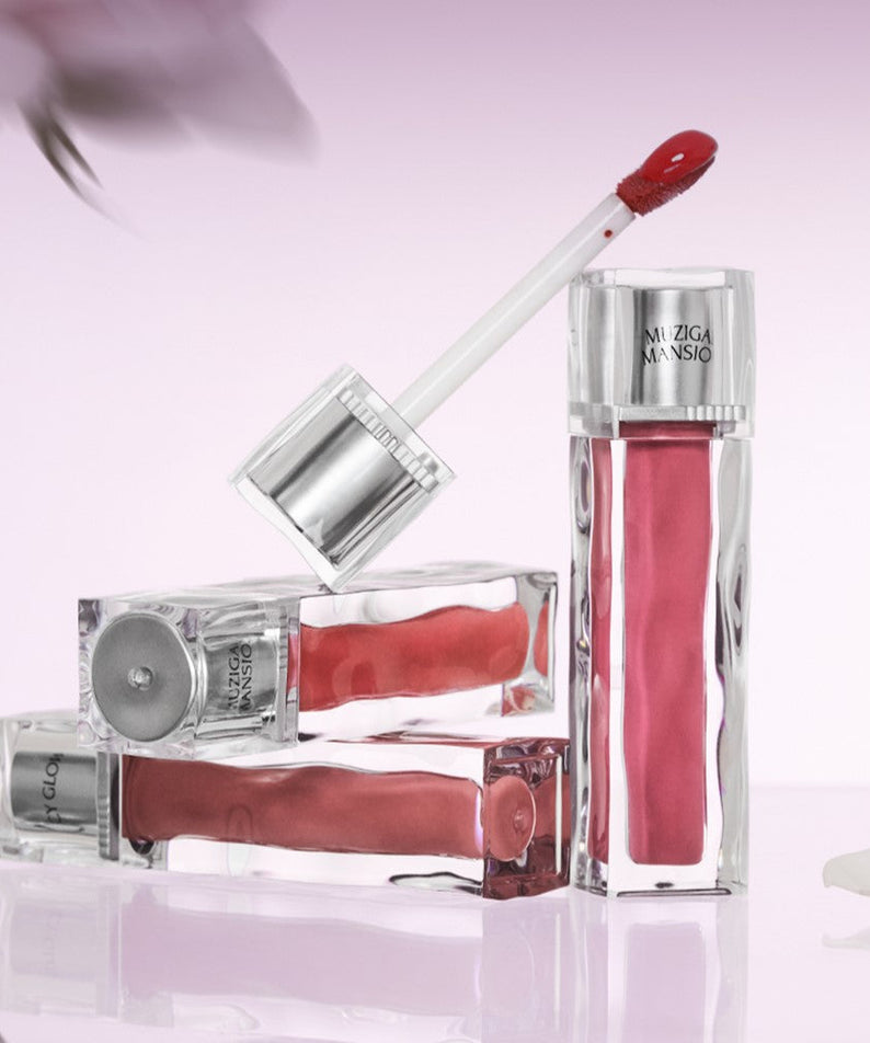 MUZIGAE MANSION Icy Glow Tint in elegant silver packaging on a pastel pink background, showcasing sleek design and vibrant color.