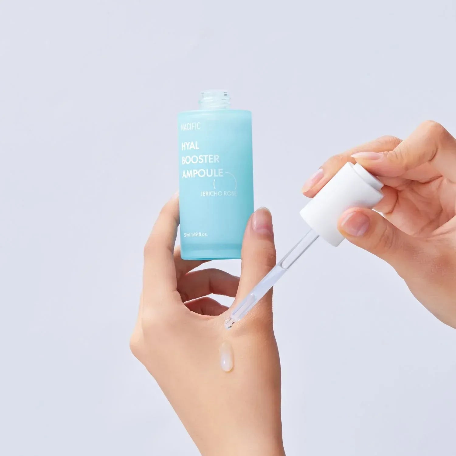Applying NACIFIC Hyal Booster Ampoule 50ml with a dropper for skincare.