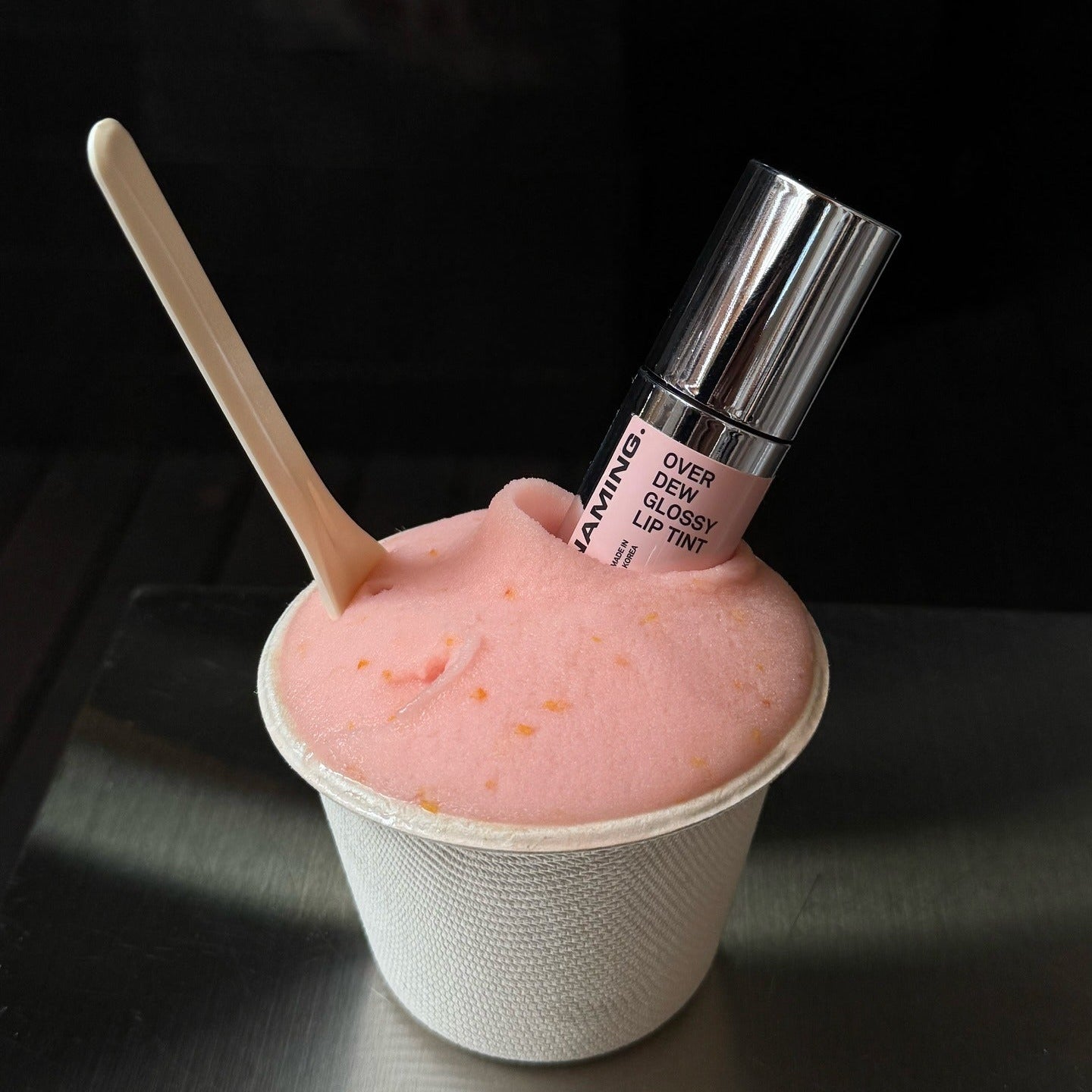 NAMING Overdew Glossy Lip Tint in pink dessert-like texture with spoon, showcasing shiny lip product.