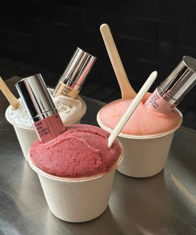 NAMING Overdew Glossy Lip Tint displayed with colorful gelato cups as a creative product presentation