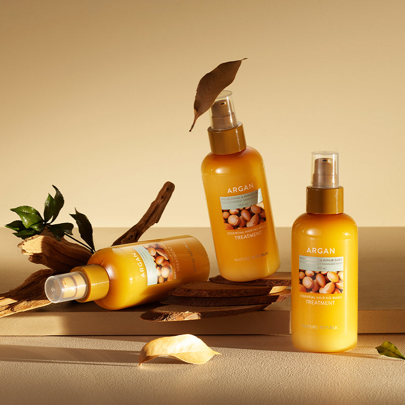 Image of NATURE REPUBLIC Argan Essential Hair No Wash Treatment 160ml bottles with natural decor on a beige surface.