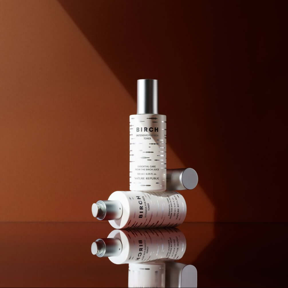 NATURE REPUBLIC Birch Intensive For Men Toner 120ml bottles on a reflective surface with a warm background.