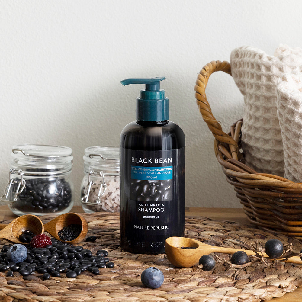 NATURE REPUBLIC Black Bean Anti Hair Loss Shampoo bottle on table with black beans and fabric basket