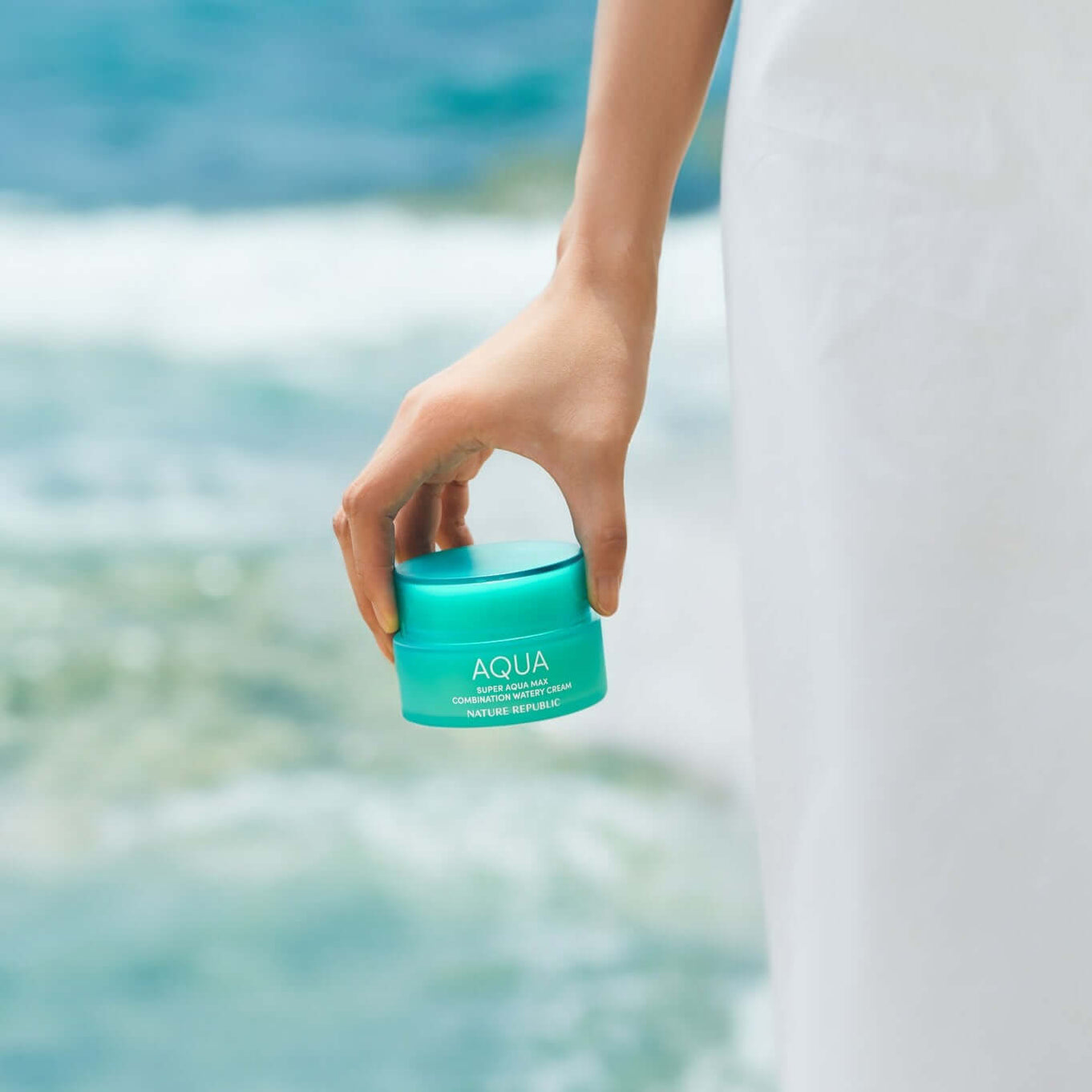 NATURE REPUBLIC Super Aqua Max Combination Moisture Cream 80ml held by hand near ocean backdrop