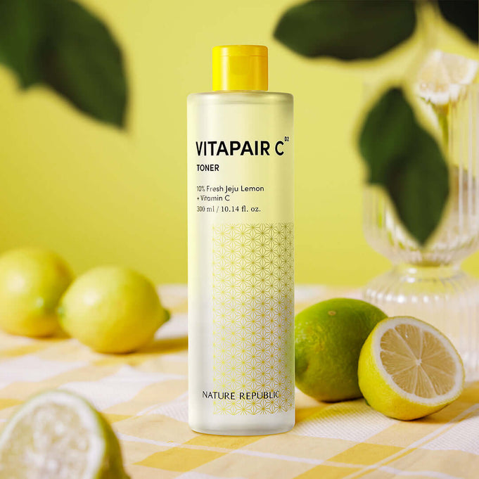 NATURE REPUBLIC VitaPair C Toner 300ml surrounded by fresh lemons on a table.