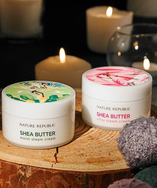 NATURE REPUBLIC Shea Butter Steam Cream 100ml placed on a wooden surface with candles in the background for a cozy ambiance.
