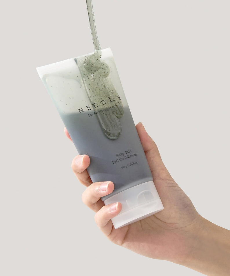 Hand holding a tube of NEEDLY Ishower Spa Mask 180g against a neutral background.