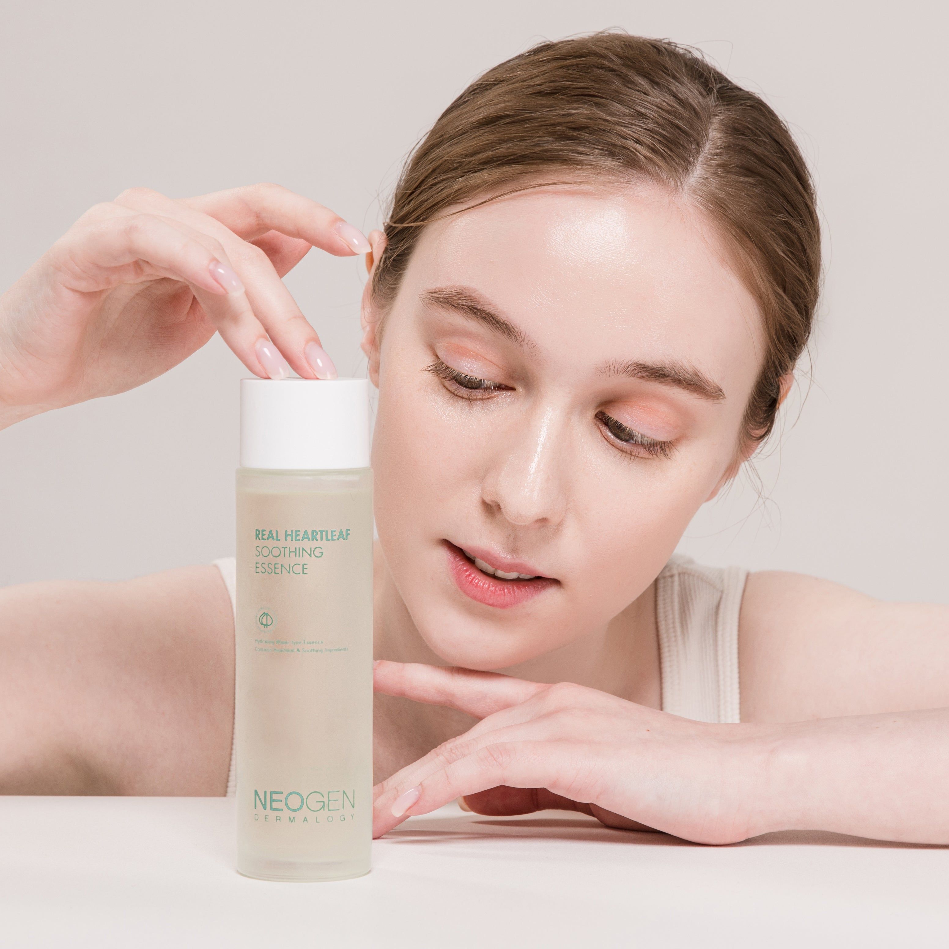 Person holding NEOGEN Real Heartleaf Soothing Essence 150ml bottle close up.