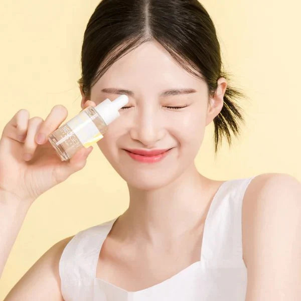 Woman holding NEOGEN Real Peptide Serum 30ml in front of a yellow background.