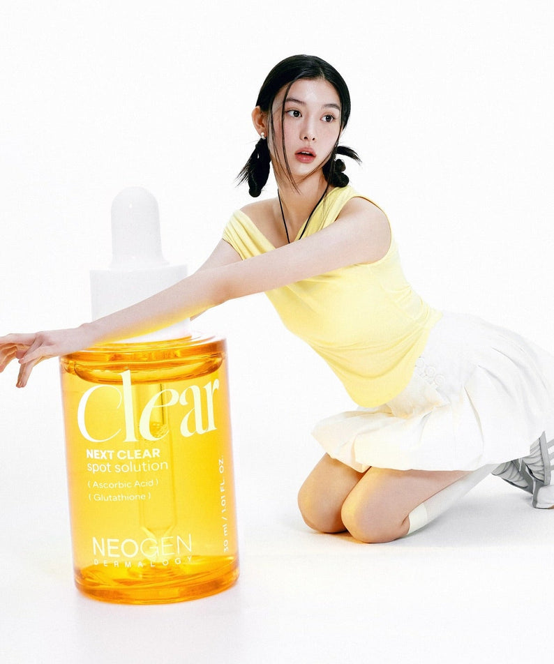 NEOGEN Next Clear Spot Solution 32ml bottle with a person in a yellow top, illustrating the product's size and design.
