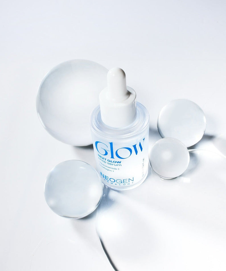 Bottle of NEOGEN Next Glow Prep Serum 32ml with surrounding spheres on a white background