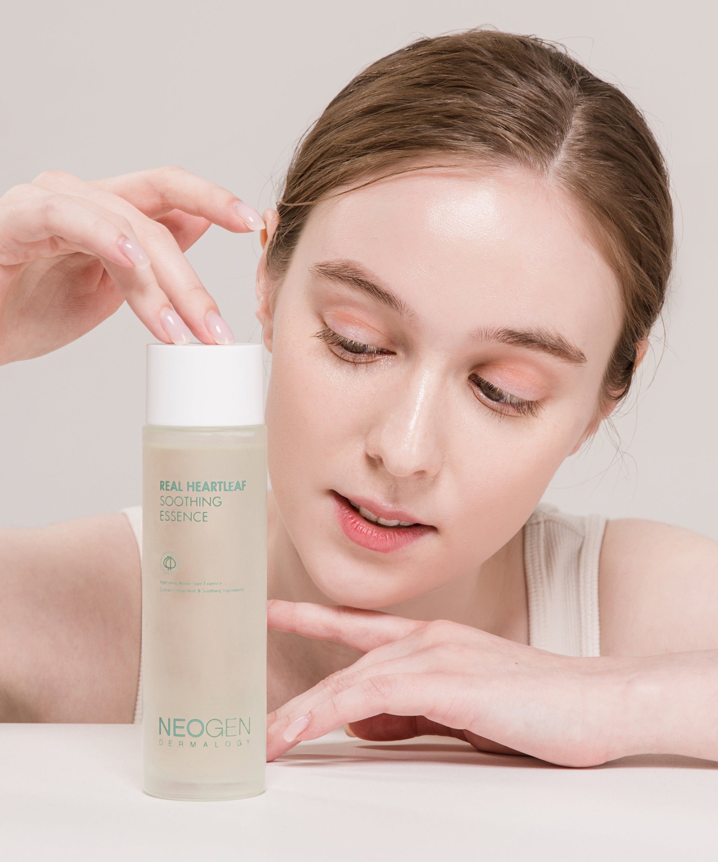 Person holding NEOGEN Real Heartleaf Soothing Essence 150ml bottle close up.