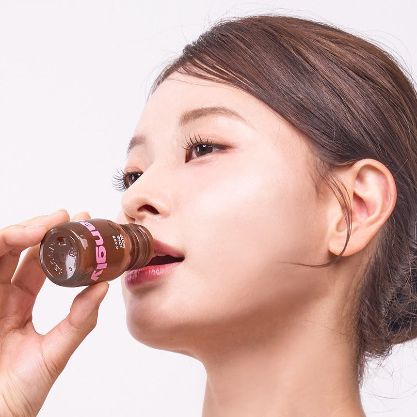 Person drinking NOTHING BETTER Tangly Glow Shot 7 Bottles, showcasing beauty and wellness benefits.