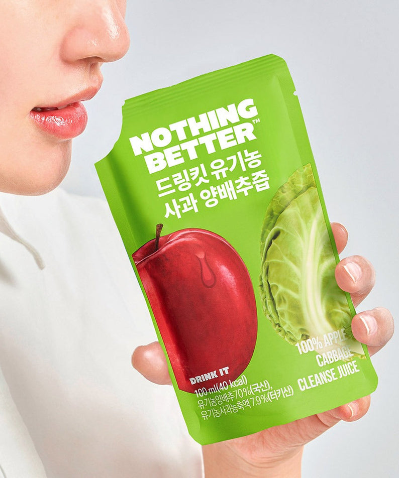 Person holding NOTHING BETTER Drinkit Organic Applr Cabbage Juice 100ml packet with apple and cabbage image on packaging.