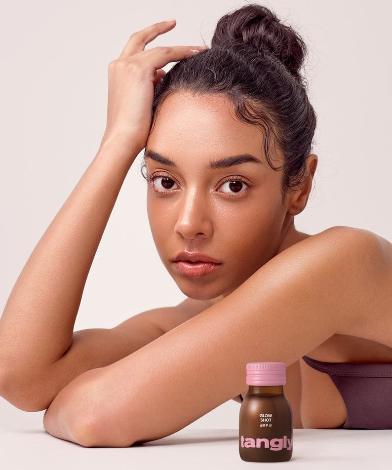 Woman next to NOTHING BETTER Tangly Glow Shot 7 Bottles, highlighting skincare benefits of the Tangly Glow product shot.