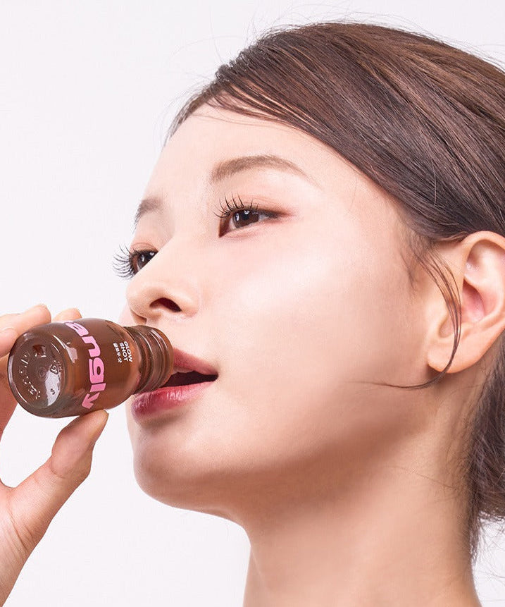 Person drinking NOTHING BETTER Tangly Glow Shot 7 Bottles, showcasing beauty and wellness benefits.