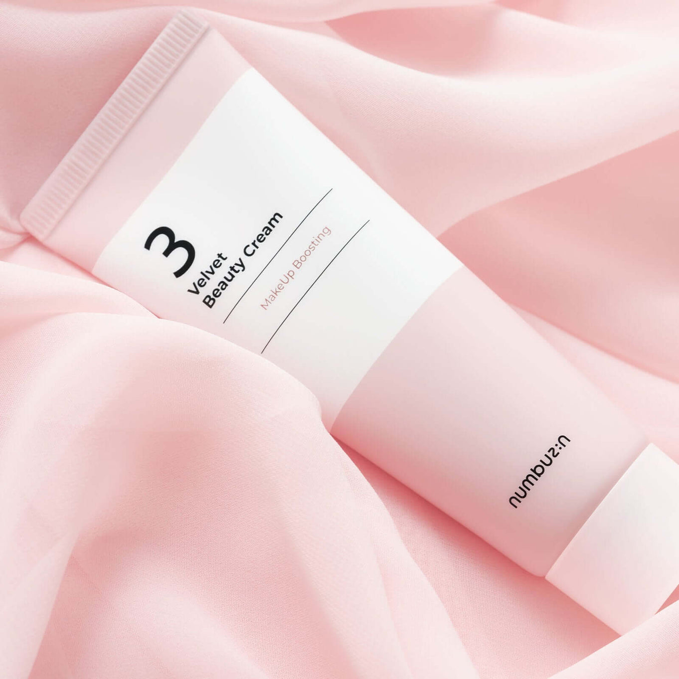 NUMBUZIN No.3 Velvet Beauty Cream tube on pink fabric backdrop.