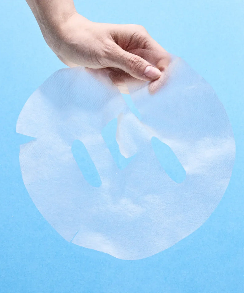 Hand holding NUMBUZIN No.1 Hyaluronic Panthenic Acid Clear Soothing Gauze Pack sheet against blue background.