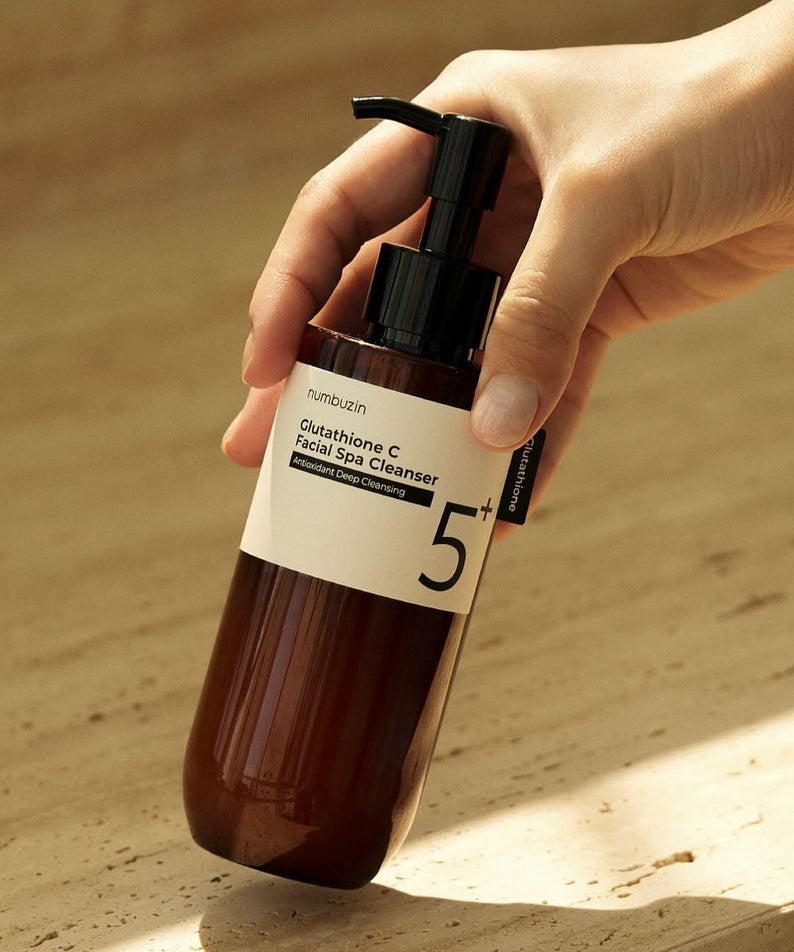 Hand holding NUMBUZIN No.5 Glutathione C Aroma Massage Deep Cleanser 200ml bottle on a beige background