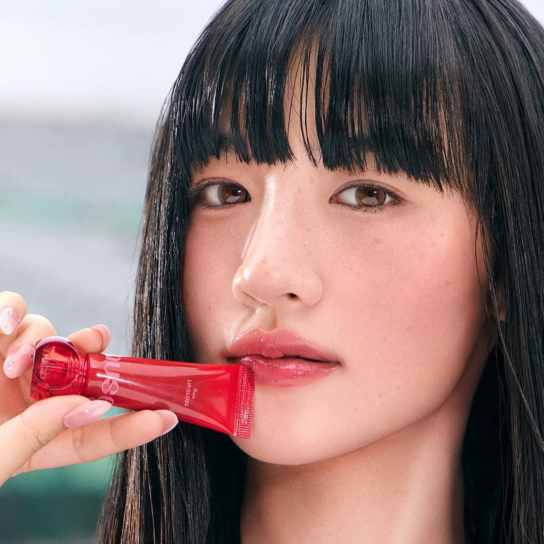Close-up of a person holding NUSE Nuzzle Reju Lip Gloss with focus on lips.