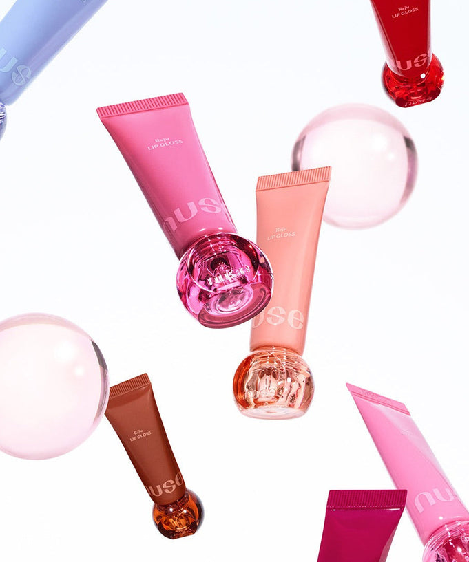 Colorful tubes of NUSE Nuzzle Reju Lip Gloss floating with bubbles on a white background.