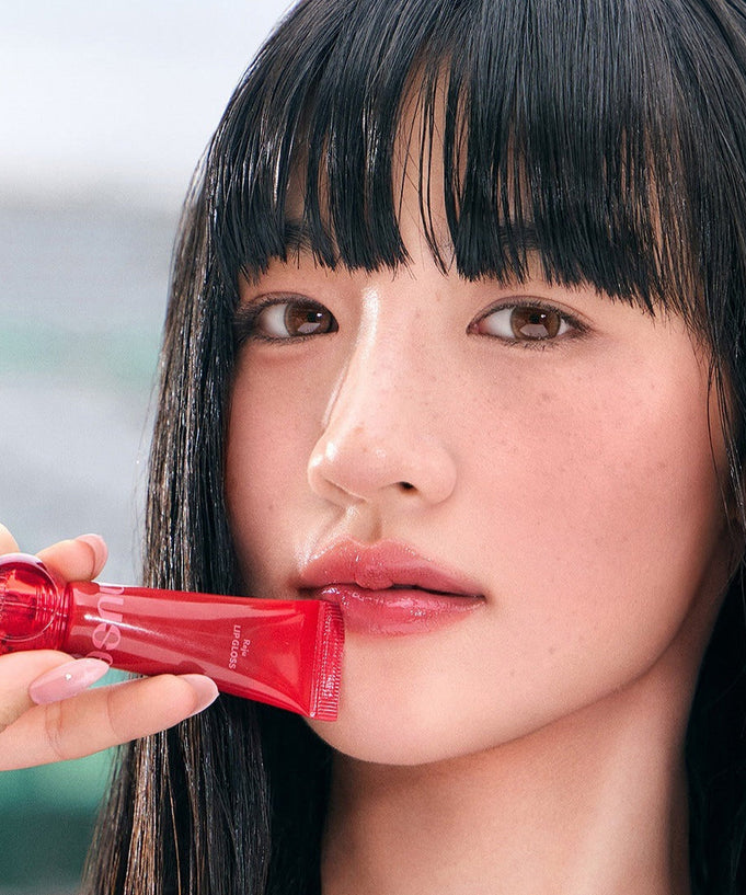 Close-up of a person holding NUSE Nuzzle Reju Lip Gloss with focus on lips.