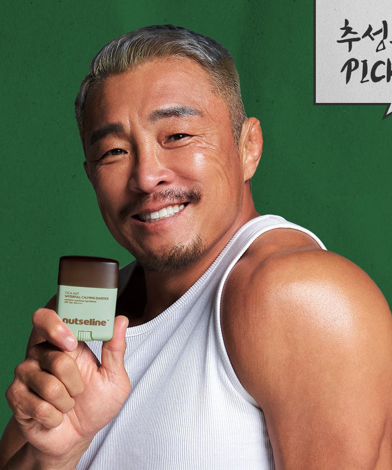 Smiling man holding NUTSELINE Cica Nut Waterful Calming Sun Stick 20g against a green background.