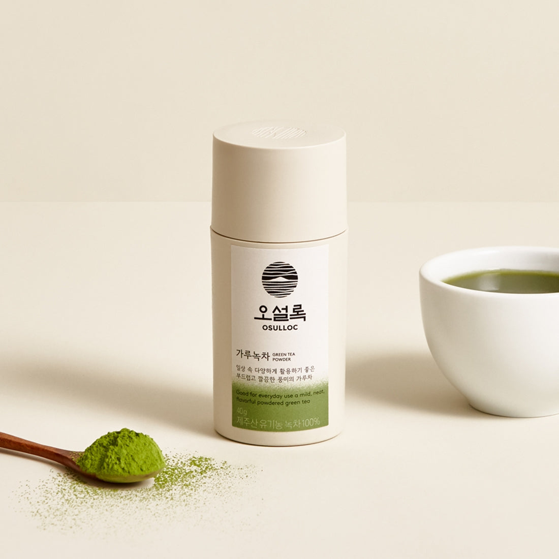 OSULLOC Green Tea Powder 40g container with spoon and cup of green tea on a beige background