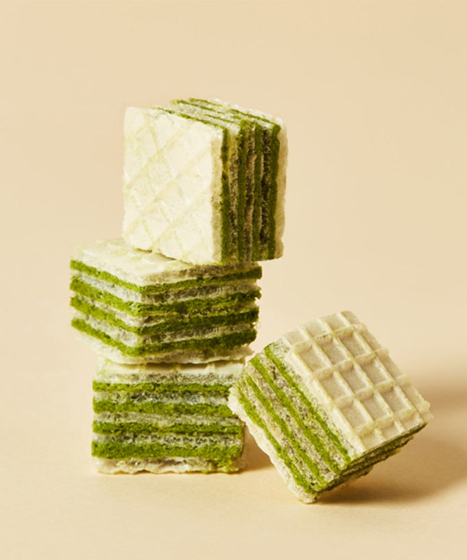 Stack of OSULLOC Green Tea Wafers 100g on a beige background