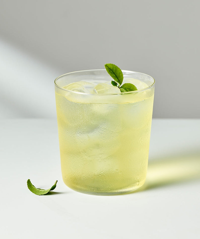 Glass of iced OSULLOC Jeju Pure Green Tea 20 P with mint leaves on white table