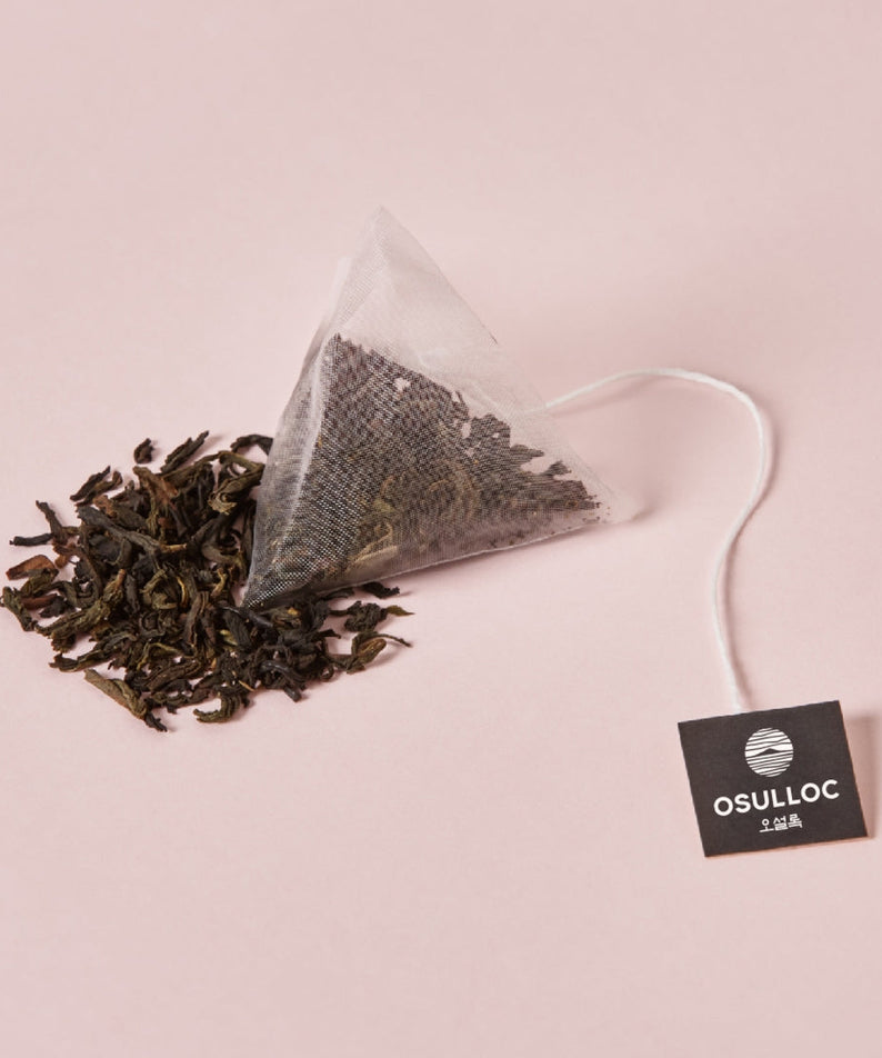 OSULLOC Milky Oolong Tea 10 p. teabag with loose leaves on a pink background.