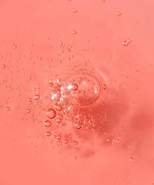 Close-up of PARNELL AHA 9.12 Caremic Wash-Off Serum 30ml texture with bubbles against a pink background