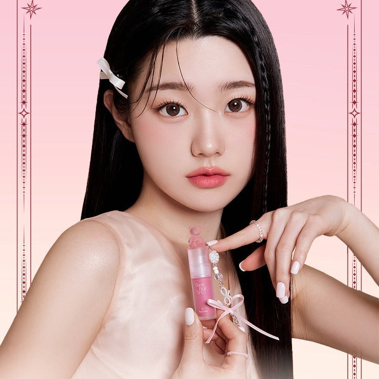 Model holding PASSION CAT Bere Blur Tint against a pink gradient backdrop, showcasing vibrant lip color.