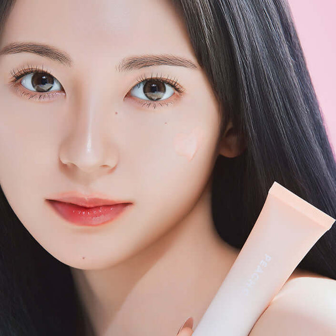 Close-up of a woman holding PEACH C Beige Glow Makeup Base, showcasing luminous skin with the product applied.