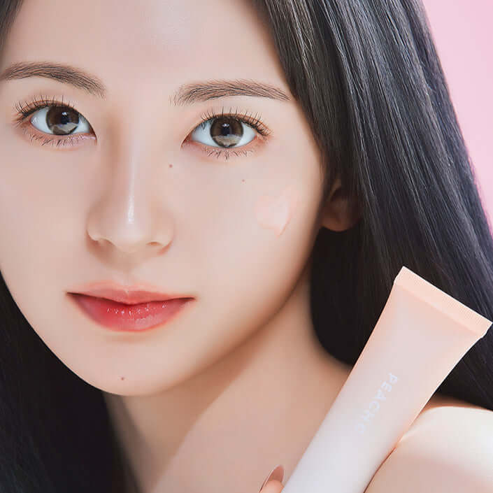 Close-up of a woman holding PEACH C Beige Glow Makeup Base, showcasing luminous skin with the product applied.