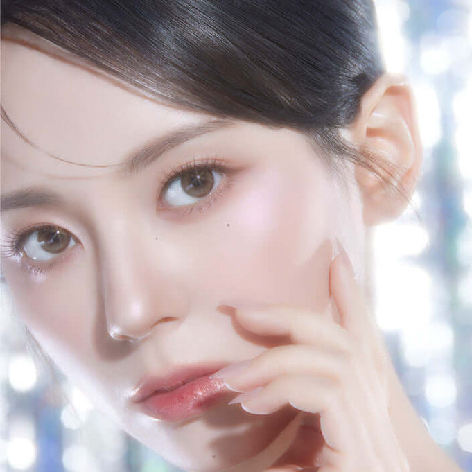 Close-up of model wearing PEACH C Dual Beam Highlighter for a radiant glow.
