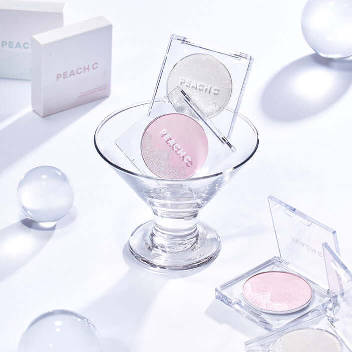 PEACH C Dual Beam Highlighter in a glass dish with packaging and shimmering shades on display.