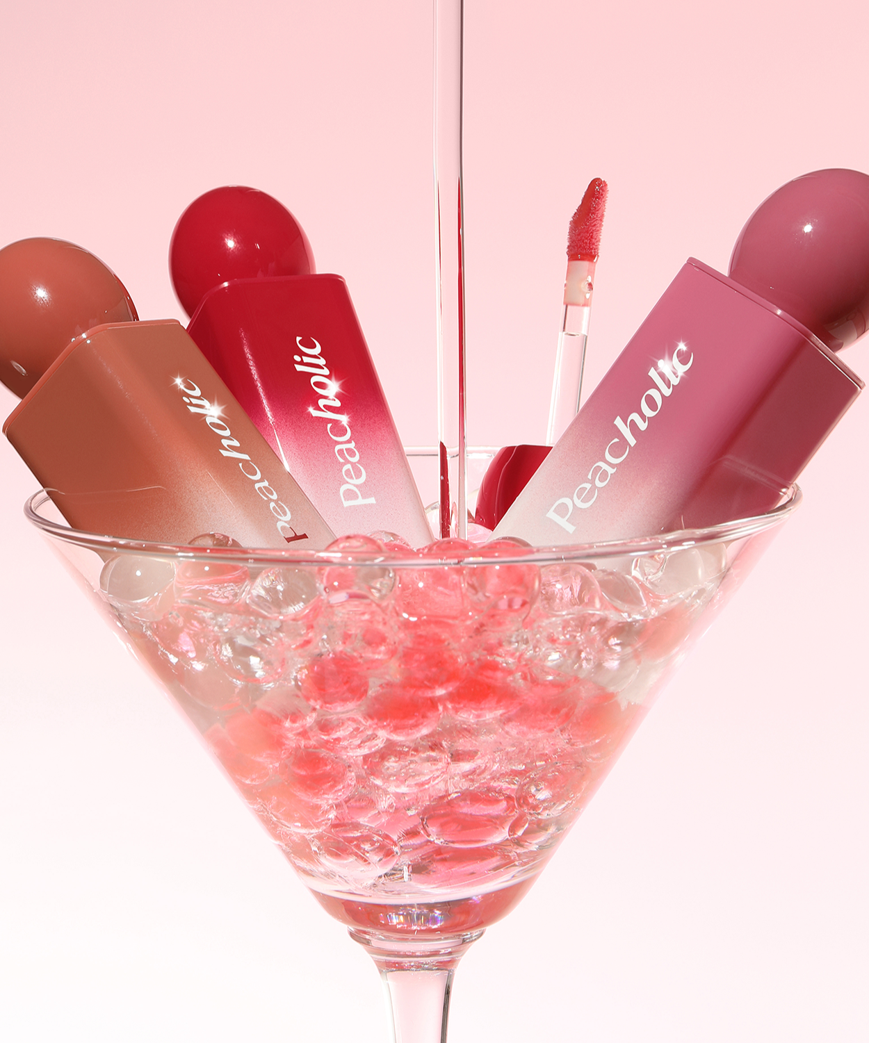 PEACHOLIC Water Glow Lip Tint in various shades displayed in a martini glass with pink and red accents.