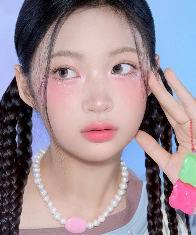 Model wearing PERIPERA Talk Blush Keycap, showcasing vibrant blush tones on cheeks and stylish braided hairstyle with pearl necklace.