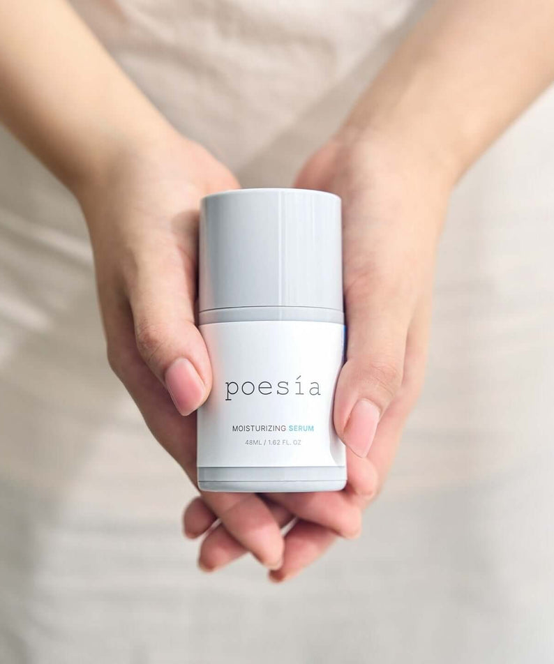 Hands holding POESÃA Hydro Hyaluronic Deep Moisturizing Ampoule Serum 48ml bottle.