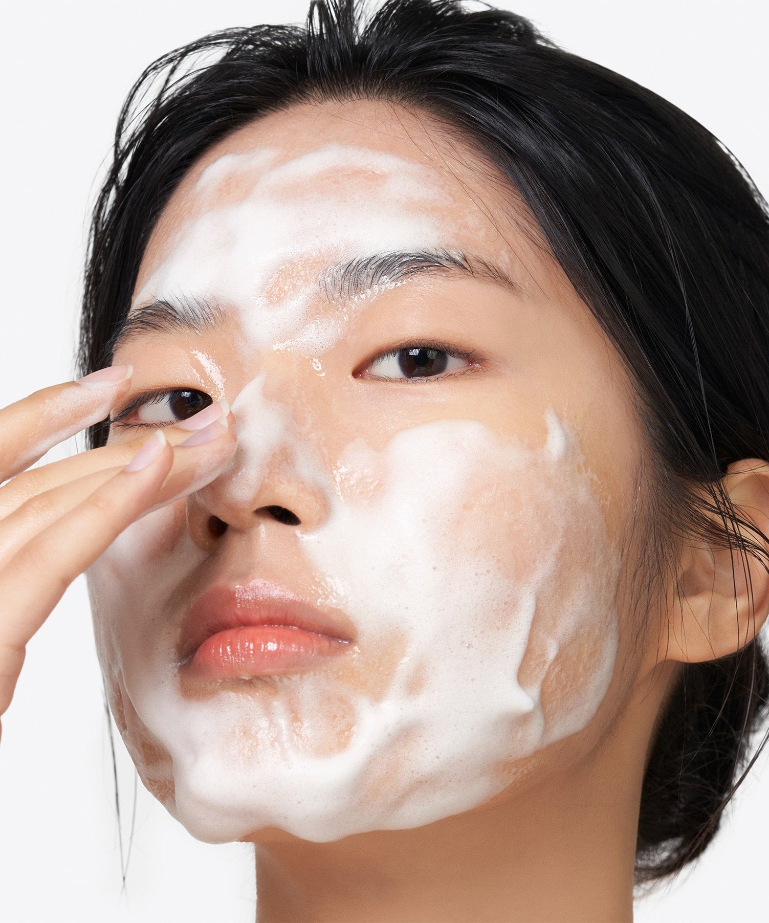 Woman applying PURITO Clear Code Superfruit Cleanser 150ml, demonstrating its foaming texture and skincare benefits.