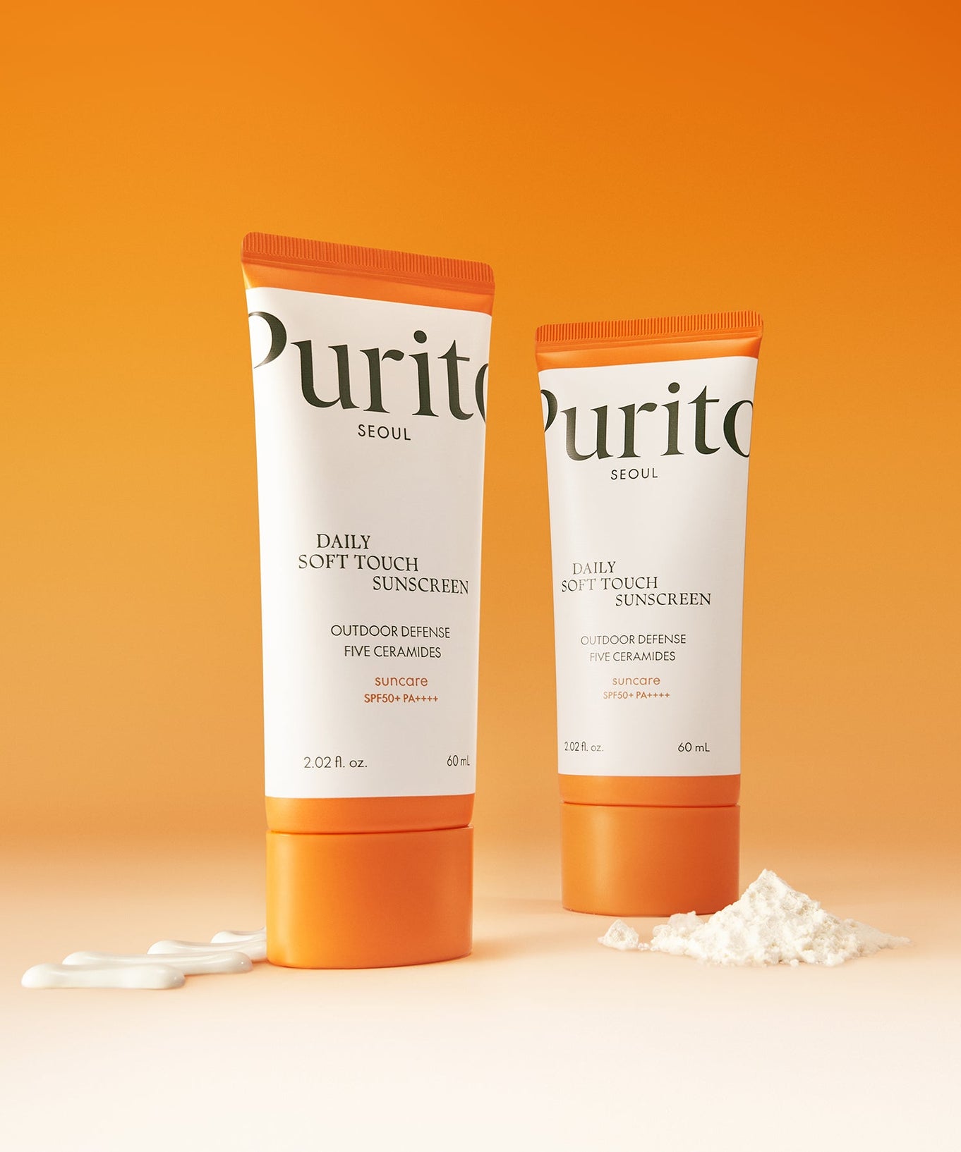 PURITO Daily Soft Touch Sun Cream SPF50+PA++++ tubes on a gradient orange background with cream and powder accents