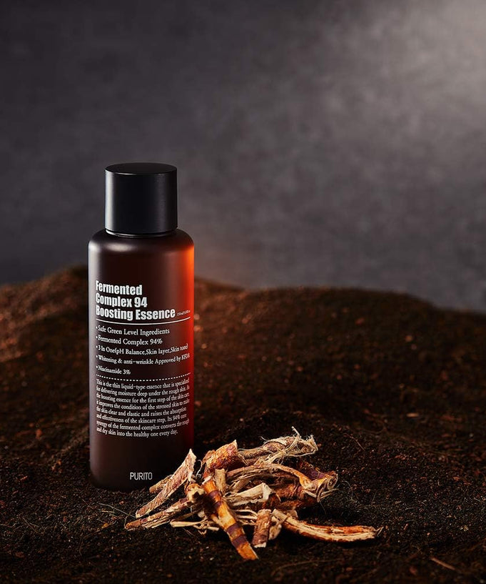 PURITO Fermentedd Complex 94 Boosting Essence 150ml bottle on dark soil background with plant roots.
