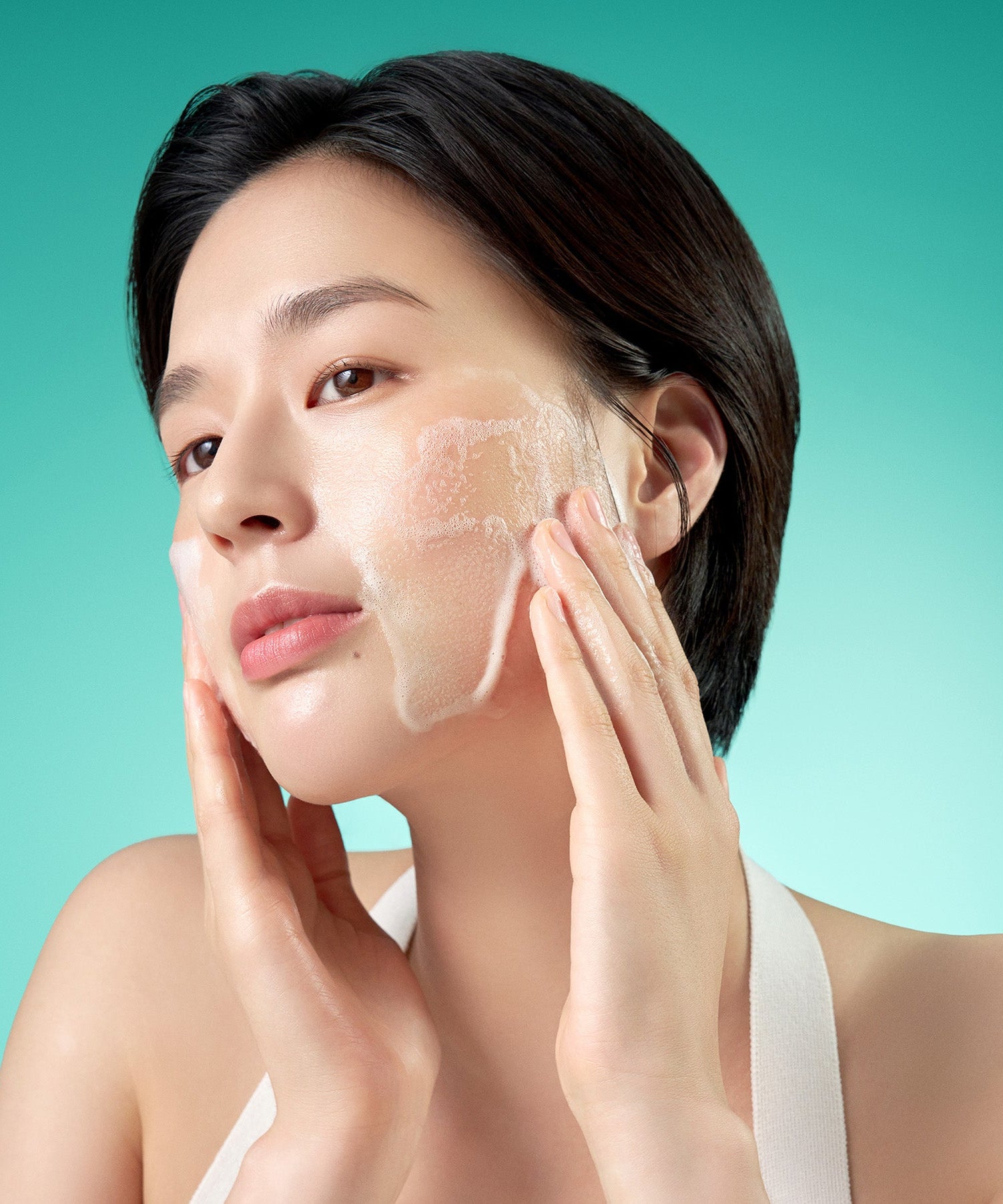 Woman using PURITO Mighty Bamboo Panthenol Cleanser 150ml, demonstrating lathering on skin for skincare routine.
